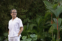 Mature men dressed in white, standing in garden, hands in pockets - Asia Images Group