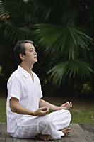 Mature man sitting outdoors practicing Yoga - Asia Images Group