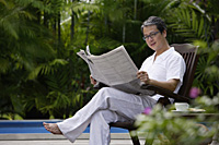 Mature man sitting outdoors, reading newspaper - Asia Images Group