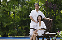 Couple relaxing outdoors by swimming pool, looking at camera, portrait - Asia Images Group