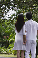 Couple in garden, holding hands, rear view - Asia Images Group