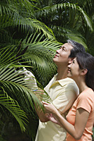 Couple outdoors in garden, studying palm plant - Asia Images Group