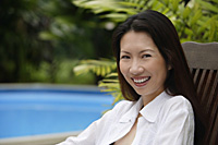 Woman sitting outdoors, smiling at camera - Asia Images Group