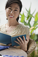 Woman holding a book, smiling at camera - Asia Images Group