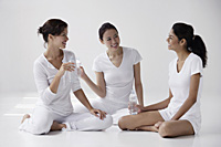 three women of mixed race sitting on floor holding water and talking - Asia Images Group