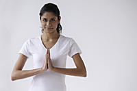 Woman standing with hands in namaste, prayer, looking at camera - Asia Images Group