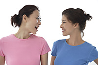 two women looking at each other, smiling - Asia Images Group