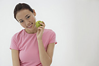 woman holding apple, smiling at camera - Asia Images Group