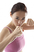Woman standing in fighting position, boxing, looking at camera - Asia Images Group