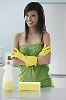 woman in kitchen with cleaning products, arms crossed, smiling at camera - Asia Images Group
