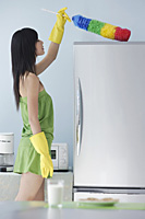 woman in kitchen, dusting, cleaning, top of fridge - Asia Images Group