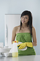 woman in kitchen, washing dishes, smiling at camera - Asia Images Group