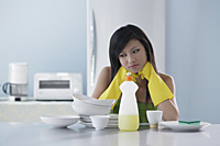 woman in kitchen, looking at pile of dishes, thinking - Asia Images Group
