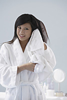 woman wearing bathrobe, towel drying hair, smiling at camera - Asia Images Group