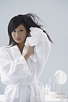 woman wearing bathrobe, towel drying hair, looking at camera - Asia Images Group