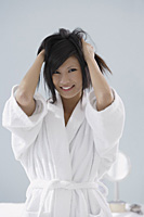 woman wearing bathrobe and running hands through hair, smiling - Asia Images Group