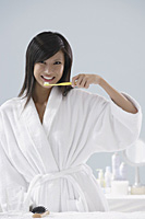 woman wearing bathrobe, brushing teeth in bathroom - Asia Images Group
