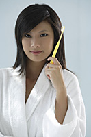 woman holding toothbrush, looking at camera - Asia Images Group