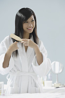woman in bathrobe, brushing hair and smiling - Asia Images Group