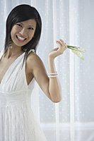 woman in white dress holding flowers and laughing, smiling - Asia Images Group