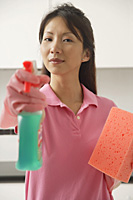 Woman cleaning with cleaning spray and sponge, spraying at camera - Asia Images Group