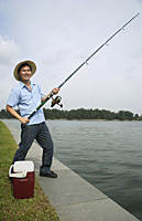 Man fishing with fishing pole, looking at camera, smiling - Asia Images Group