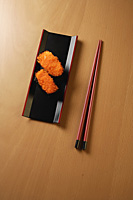 two pieces of sushi, chopsticks, tobiko gunkan, fish roe - Asia Images Group