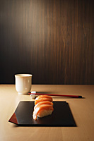 four pieces of salmon sushi on tray, nigiri on rice ball, chopsticks and tea - Asia Images Group