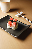 2 pieces of sushi, Kanikama Nigiri, crabstick on tray with chopsticks and tea - Asia Images Group