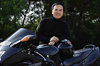 Man standing by black motorcycle, smiling at camera - Asia Images Group