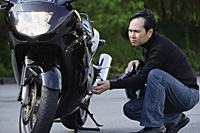 Man looking at motorcycle - Asia Images Group