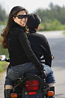 Mature couple on motorcycle, woman looking over shoulder at camera - Asia Images Group