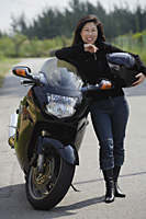 Mature woman leaning against motorcycle, holding helmet - Asia Images Group