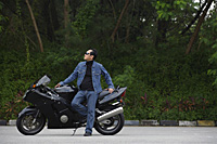 Mature man leaning against motorcycle, wearing sunglasses - Asia Images Group