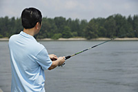 Man fishing with fishing pole, rear view - Asia Images Group