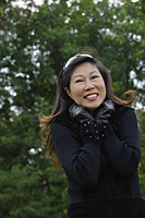 Mature woman wearing leather gloves and smiling at camera, cold - Asia Images Group