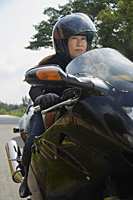 Mature woman riding motorcycle, wearing helmet - Asia Images Group