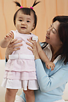 mother and baby girl, mother looking at girl, girl looking at camera - Asia Images Group