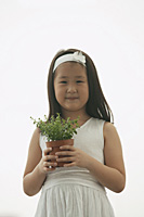 young girl holding plant, smiling, looking at camera - Asia Images Group
