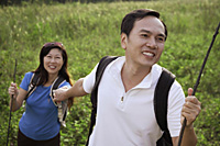 Man and woman hiking outdoors, holding hands, smiling - Asia Images Group