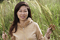 Woman in tall grass, nature, looking at camera, smiling - Asia Images Group
