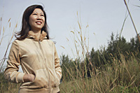 Woman standing in tall grass, nature, looking up to sky - Asia Images Group