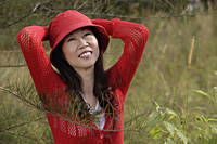 Woman wearing red hat outdoors in nature, smiling - Asia Images Group