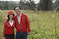 Man and woman standing outdoors in nature, smiling at camera, portrait - Asia Images Group