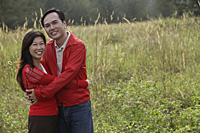 Man and woman hugging each other, standing outdoors in nature, smiling - Asia Images Group