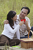 Man and woman having picnic, toasting glasses - Asia Images Group