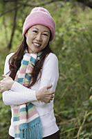 Woman outdoors wearing hat and scarf hugging herself, cold - Asia Images Group