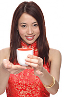Young woman wearing cheongsam, holding tea towards camera - Asia Images Group