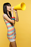 Young woman shouting through yellow megaphone - Asia Images Group