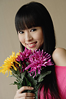 Young woman holding bouquet of flowers, smiling at camera - Asia Images Group
